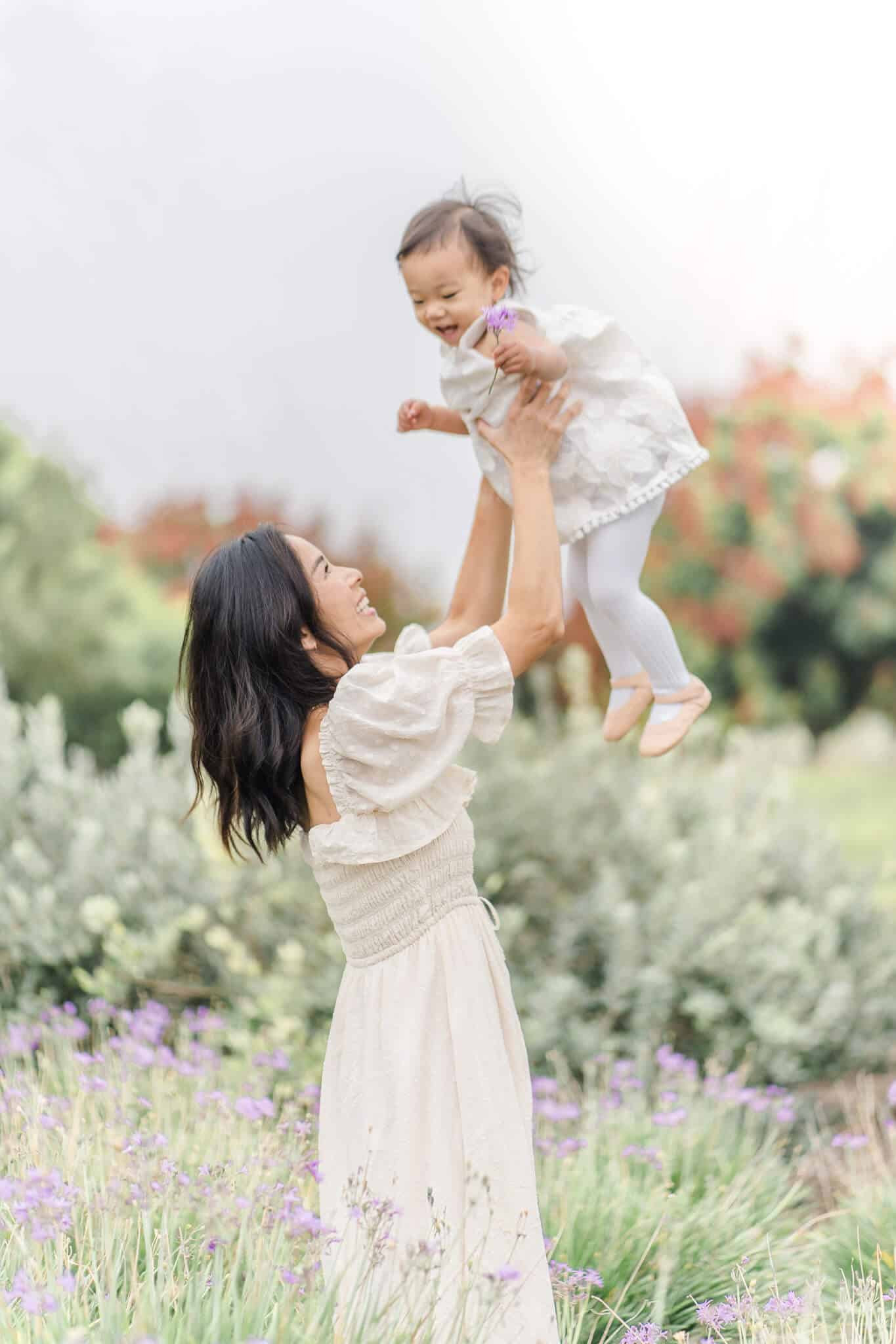 Mom tossing her 2 year old daughter into the air.