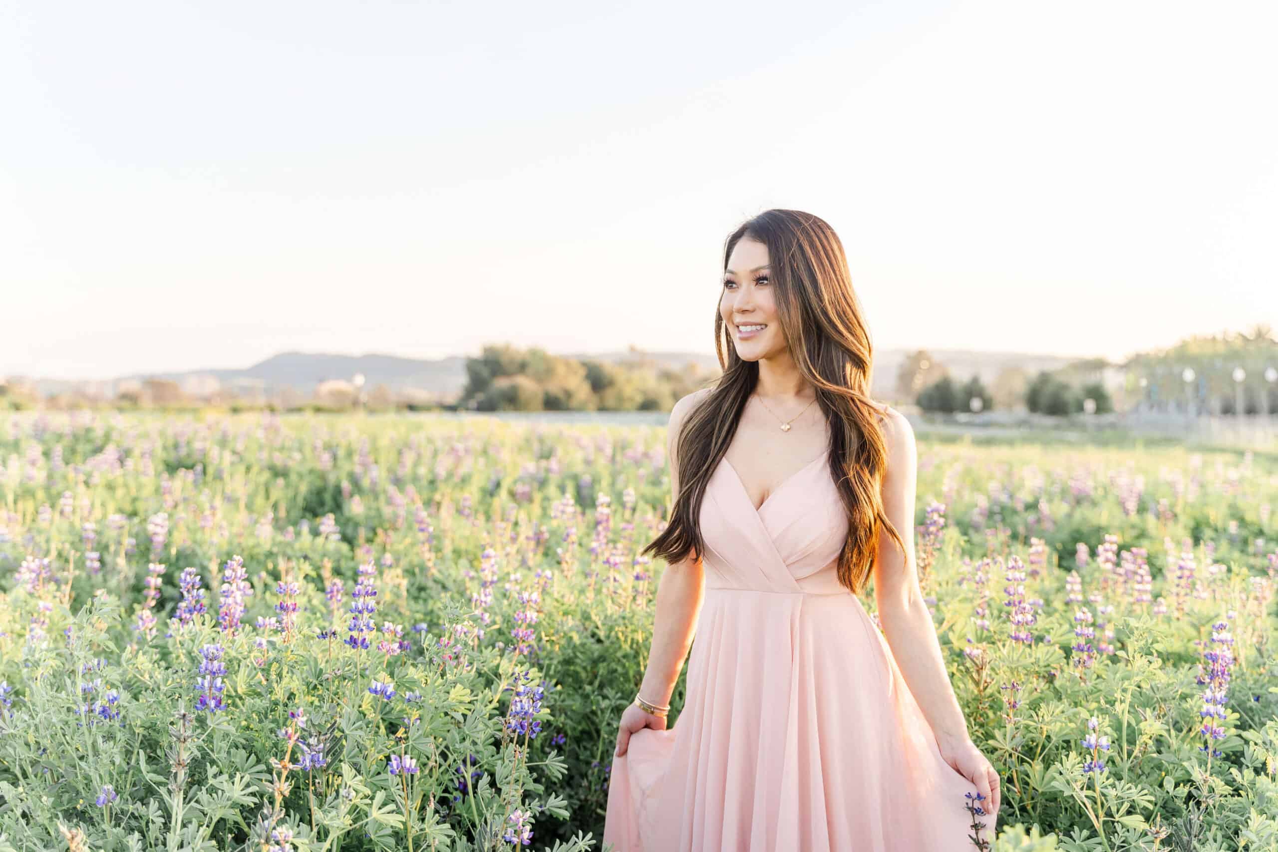 Asian woman in pink dress standing in a field of flowers