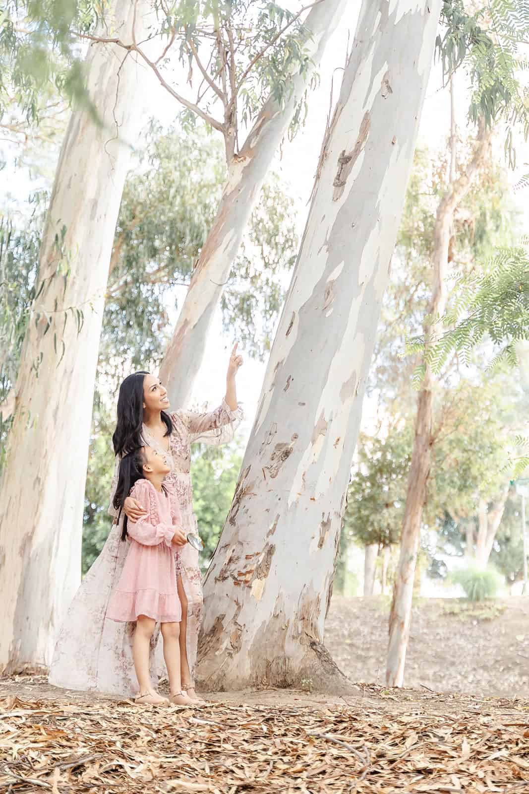 A mom shares a moment with her toddler daughter under a tree before visiting Irvine Regional Park