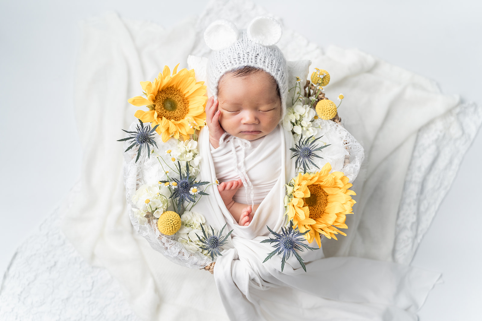 A newborn baby sleeps in a basket with sunflowers in a studio thanks to South Coast Midwifery