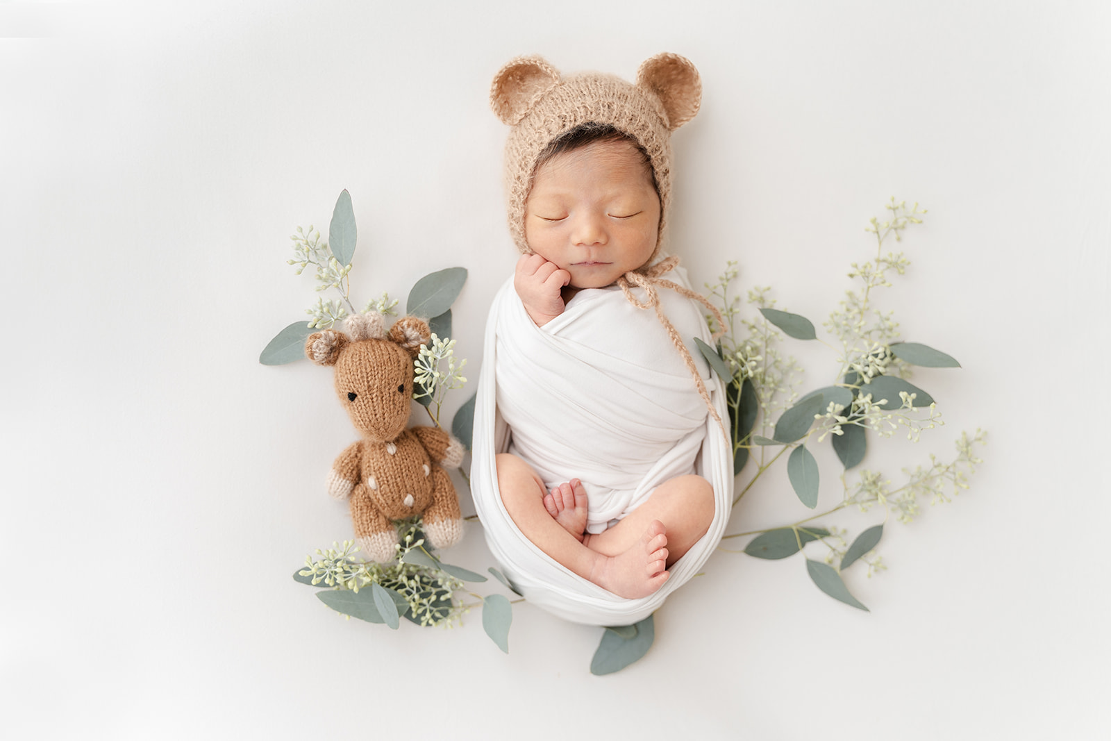 A newborn baby sleeps in a knit bonnet with bear ears in a studio thanks to Birthing Center Long Beach