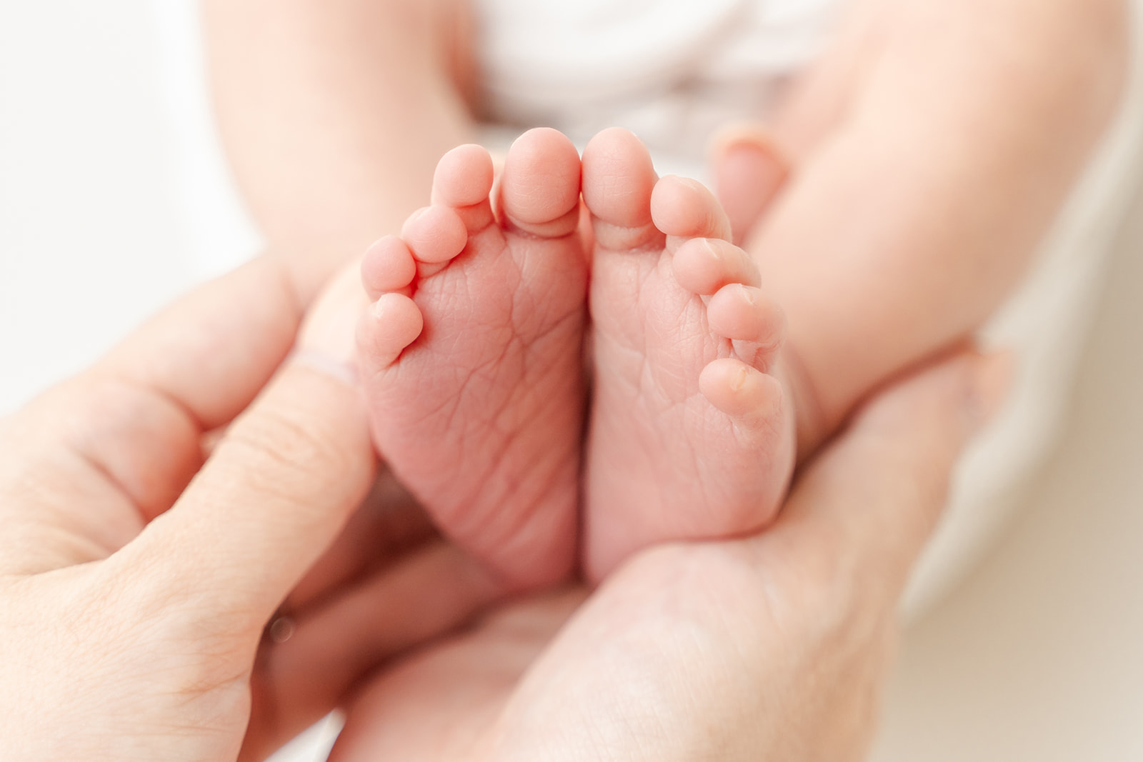 Details of a newborn baby's feet in mom's hands