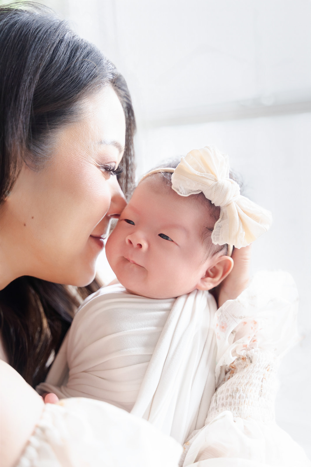 A happy new mom nuzzles her awake newborn daughter ina. whtie swaddle